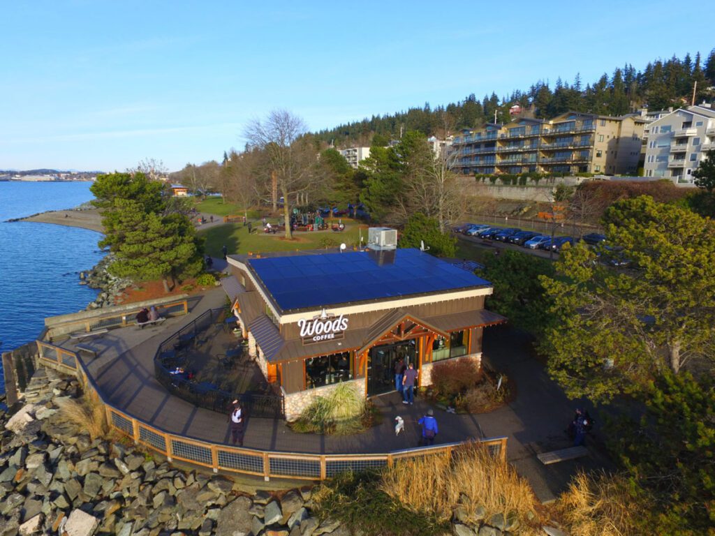 Customers enjoying the trail and deck at Woods Coffee, overlooking Bellingham Bay and powered by solar energy.